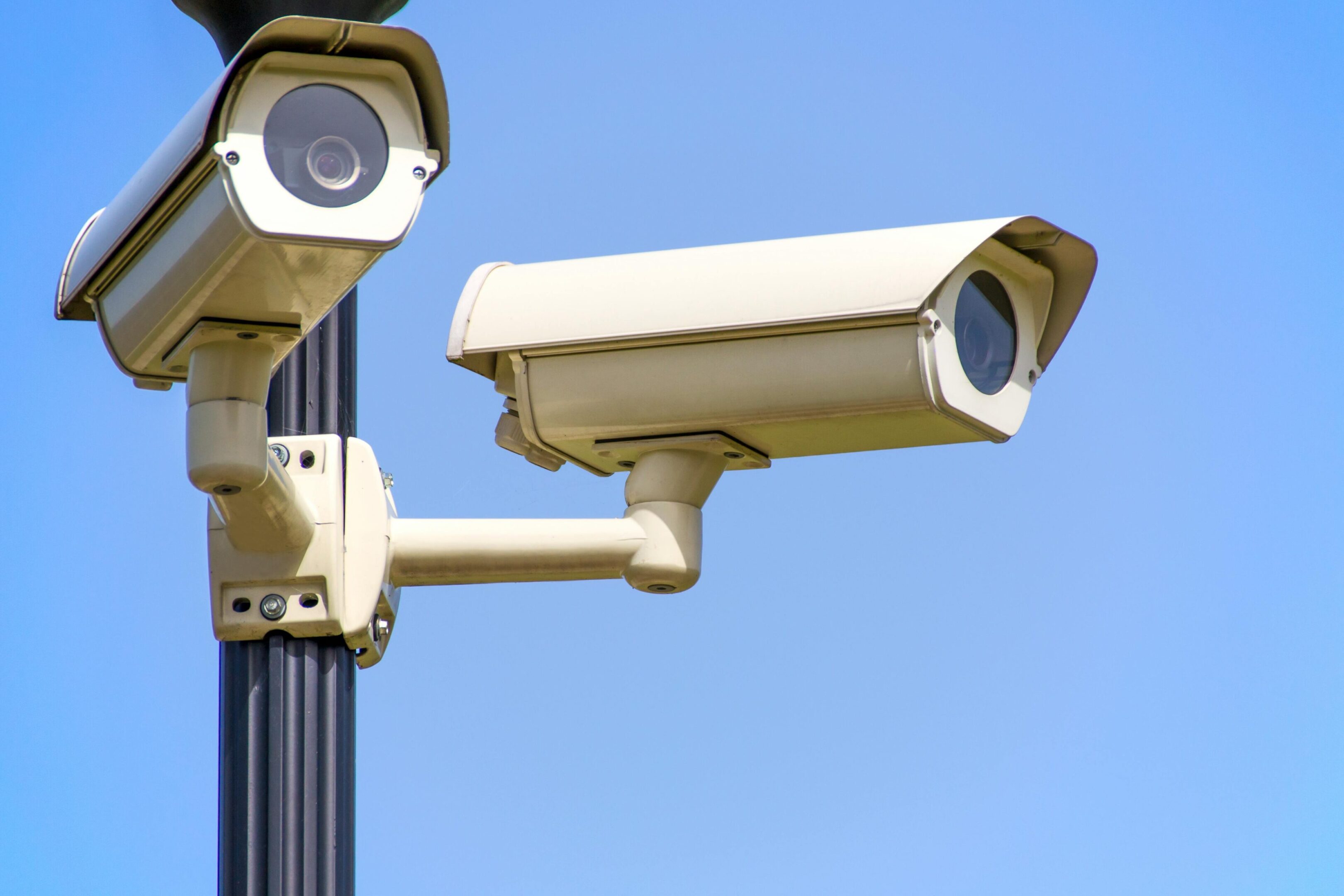 Two cameras on a pole with one of them up close.